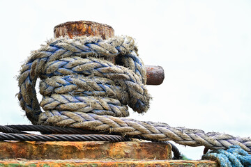 Obraz premium Weathered mooring rope wrapped around a rusty dock bollard on the Iloilo River, Iloilo, Philippines