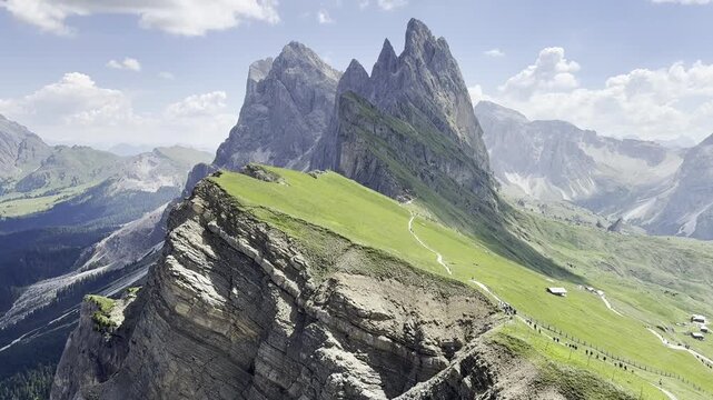 Dramatic view of iconic Seceda peaks and green ridges rising above a rugged mountain valley on a sunny summer day. Popular alpine landscape and travel destination in Dolomites, South Tyrol, Italy.