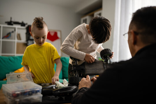 Father and sons repairing remote control car together