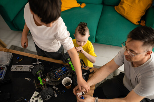 Father and sons repairing toy car, bonding at home