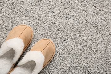 Comfort and relaxation at home, pair of soft beige slippers on a cozy grey carpet floor for a lifestyle of leisure and domestic well being © Pixel-Shot