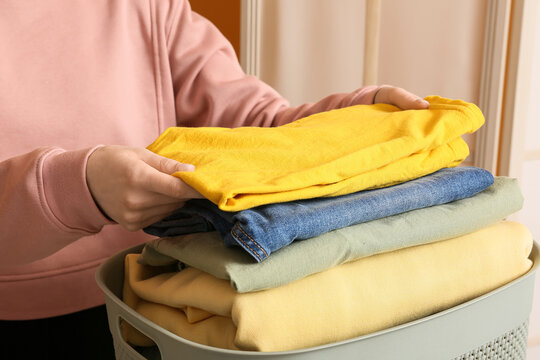 Household chores and laundry organization, person folding clean clothes into a basket for home maintenance and daily routine management in a living space