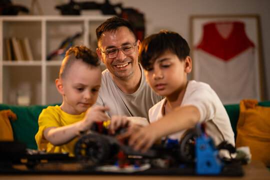 Father and sons building toy car together