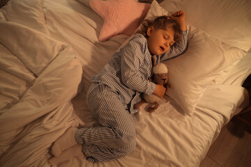 Fototapeta premium Adorable little girl with plush sheep sleeping in bed
