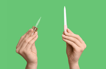 Naklejka premium Female hands with pipette for cuticle oil and nail file on green background