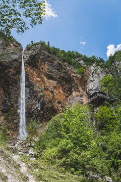 Fotografie des beeindruckenden Rinka Wasserfalls im Logartal (Logarska Dolina) in Slowenien. Das Bild zeigt den hohen, frei fallenden Wasserstrahl, der &uuml;ber eine steile Felswand in die Tiefe st&uuml;rzt.