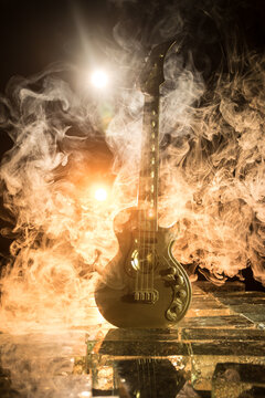 Music Concept: Guitar Miniature on a Dark Background with Vivid Light, Smoke, and Fire Effects. Golden electro guitar under a Dramatic Spotlight.