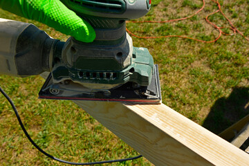 szlifowanie deski ręczną szlifierką elektryczną, szlifowanie deski na altankę, sanding the board with an electric hand sander © kateej
