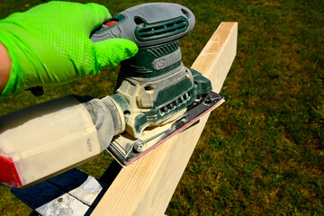 szlifowanie deski ręczną szlifierką elektryczną, szlifowanie deski na altankę, sanding the board with an electric hand sander © kateej