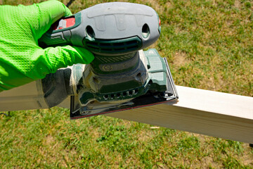szlifowanie deski ręczną szlifierką elektryczną, szlifowanie deski na altankę, sanding the board with an electric hand sander © kateej