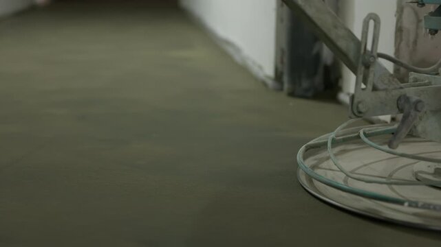 Power trowel smoothing fresh concrete floor during construction