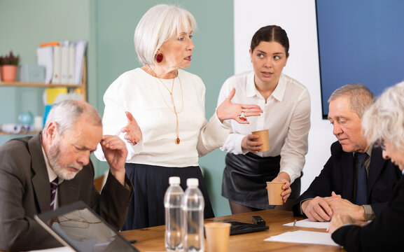 Businessman of a large company scolds his employees sitting at workdesk in the office