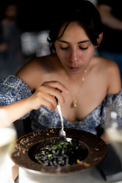 Woman enjoying black squid ink pasta in a Venice restaurant