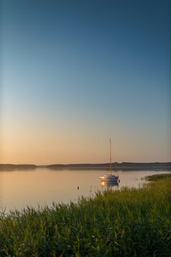Serene Sailboat Anchored on Calm Masurian Lake at Dawn with Vast Copy Space Sky