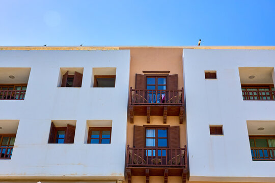 Sunlit Mediterranean-style apartment building with wooden balconies