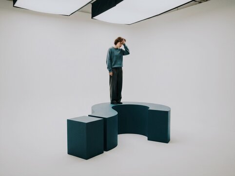 Man in sweater deep in thought in minimalist studio during artistic contemplation