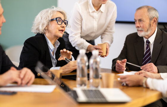 Mature business community gathering to carrying out round table meeting, chatting, talking and disputing. Working session, secretary accompanies business negotiations and serves drinks