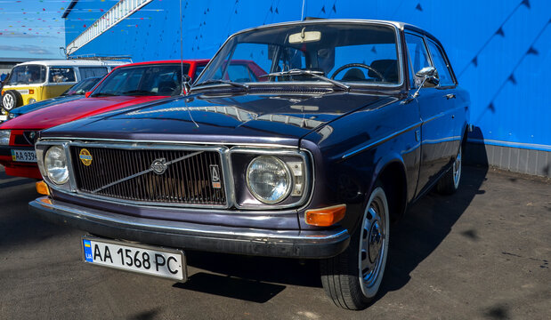 Classic vintage Volvo 142 sedan in dark purple with white roof, chrome trim, and round headlights, highlighting iconic Swedish automotive design and safety heritage