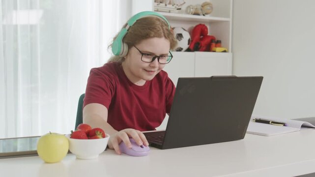Child Learning with laptop and handwritten notebook. Learning beside pencils and stacked books. Focused child learning at computer desk. Academic learning activity in home.