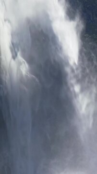 Waterfall cascades into rocky mountain stream. Waterfall splashes over natural rocky landscape. Flowing waterfall cascades across rocky cliff. Alpine water flows beneath waterfall naturally.