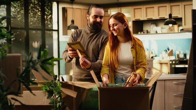 Man and woman unpack wrapped furniture and household items on relocation day, arranging belongings after moving while young homeowners enjoy a fresh start settling into their new residence together.
