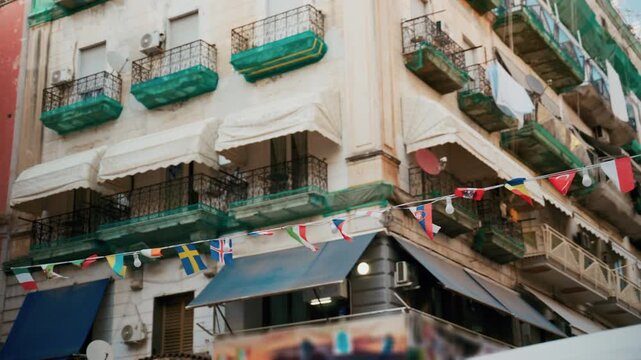 A street in Naples with small national flags strung between the buildings