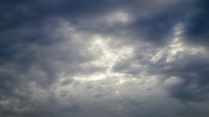 Fototapeta premium heavy grey clouds centered with a bright sunlit gap glowing through the dark sky