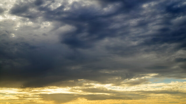 dark storm clouds juxtaposed against a warm golden sunset glow along the lower horizon