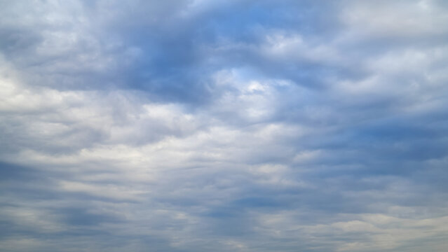 light blue daytime sky evenly covered with soft white and subtle grey cloud layers