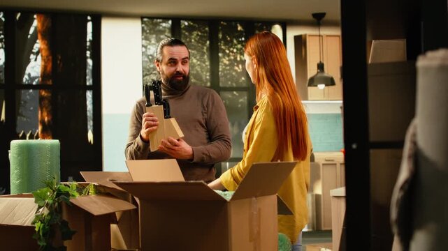 Couple unpacking decorations and belongings in their first home, enjoying moving day, residential settlement and the satisfaction of decorating new rooms.