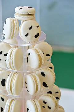 cow print macarons tower on clear acrylic display tier, farm theme birthday party dessert setup, gourmet French macaron display close up