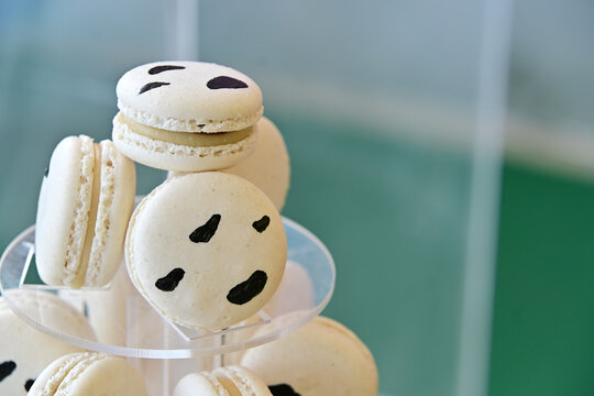 cow print macarons tower on clear acrylic display tier, farm theme birthday party dessert setup, gourmet French macaron display close up