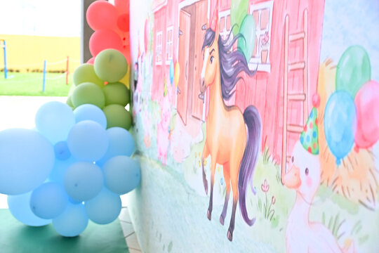 farm theme birthday party backdrop illustration with brown horse and red barn beside colorful balloon garland, event decoration close up
