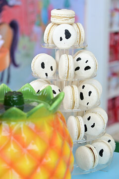 cow print macarons tower on clear acrylic display tier, farm theme birthday party dessert setup, gourmet French macaron display close up