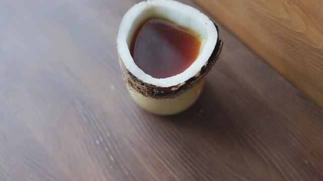 Alternative manual coffee brewing inside a natural carved coconut shell on a rustic surface
