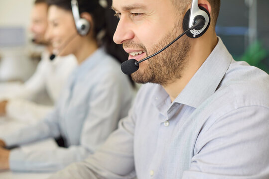 Operator with headset handles customer support call. Professional male agent at computer in bright office, engaging clients with friendly communication and service. Team help and care concept.