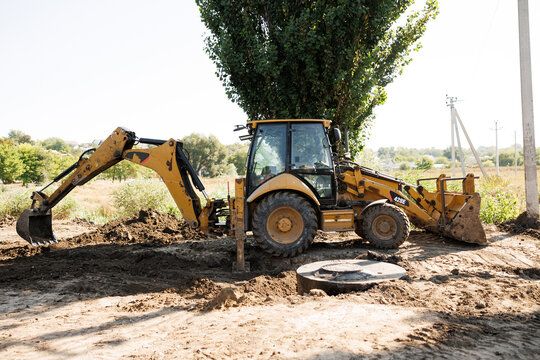 Yellow backhoe loader digging at outdoor construction site for ground excavation and development