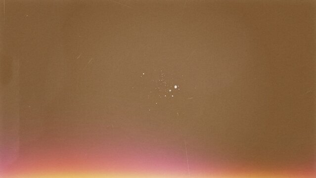Warm brown vintage 35mm film grain texture with a soft pink light leak and scattered dust specks