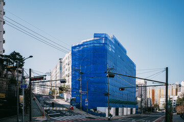 Building under construction covered with blue safety netting © kwangchan