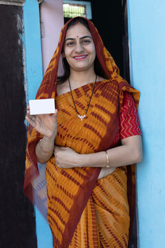 Portrait of Indian rural young woman showing unique identity card at village. Indian rural woman showing Aadhar card at home. Concept of rural woman empowerment in india.