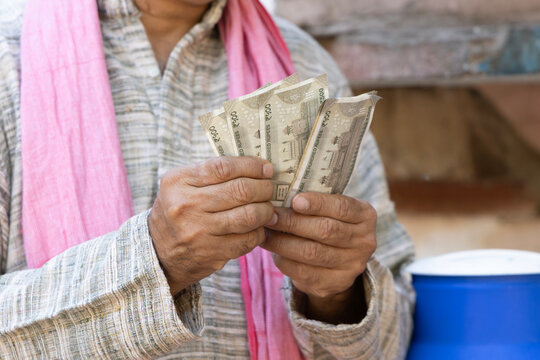 Close-up of an Indian rural farmer counting Indian rupee banknotes at home, representing agricultural income, cash savings, rural economy, financial planning, and livelihood.
