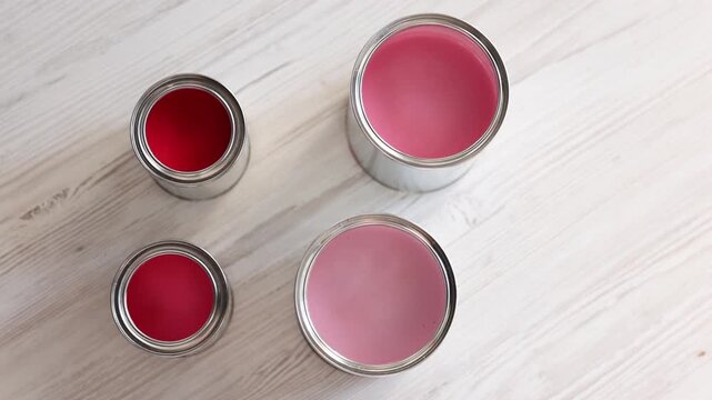 Cans with paint in shades of pink on white wooden table, flat lay