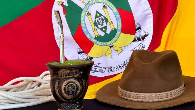 Chimarr&atilde;o, gaucho hat and scarf on the table, and the flag of the state of Rio Grande do Sul - Brazil  in the background. Farroupilha Week.