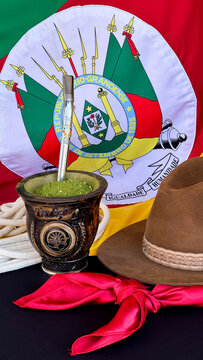 Chimarr&atilde;o, gaucho hat and scarf on the table, and the flag of the state of Rio Grande do Sul - Brazil  in the background. Farroupilha Week.