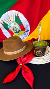 Chimarr&atilde;o, gaucho hat and scarf on the table, and the flag of the state of Rio Grande do Sul - Brazil  in the background. Farroupilha Week.