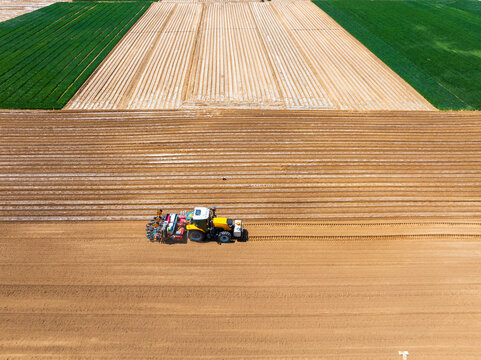 In spring, farmers use farm machinery to grow peanuts，Aerial photos of farmers using agricultural machinery to cultivate the land.