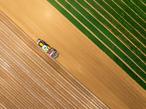 In spring, farmers use farm machinery to grow peanuts，Aerial photos of farmers using agricultural machinery to cultivate the land.