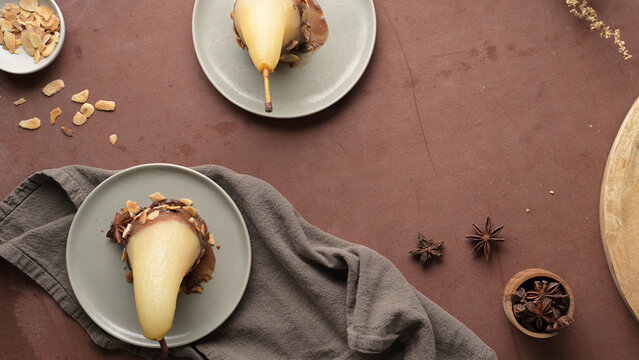 Poached pears with chocolate and almonds on plates