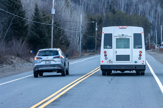 Quebec, Canada, 24 April 2026 : A silver Toyota SUV follows a white bus from Ecole Forestiere de La Tuque on a rural road.