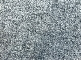 Full frame close-up texture of dense grey synthetic felt fabric with fibrous surface detail. © Akram